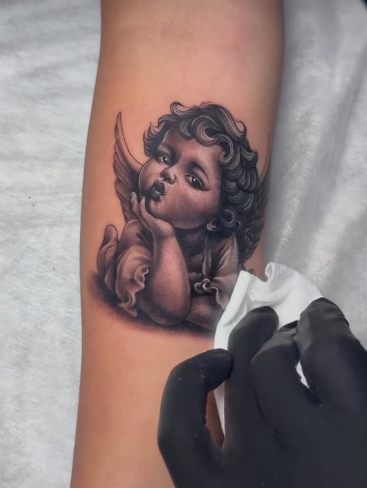 Realistic black and grey cherub tattoo