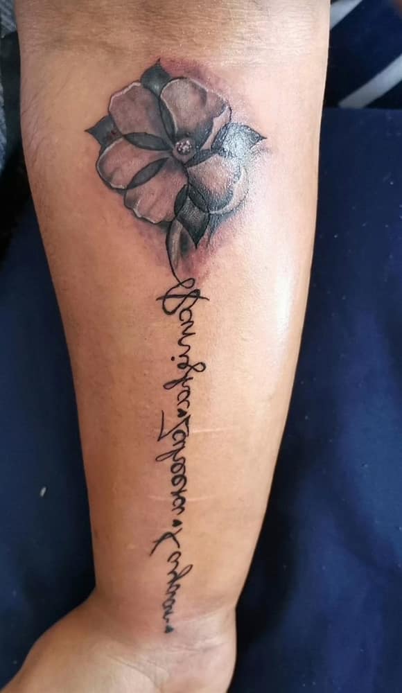 Black and grey floral tattoo with flowing script